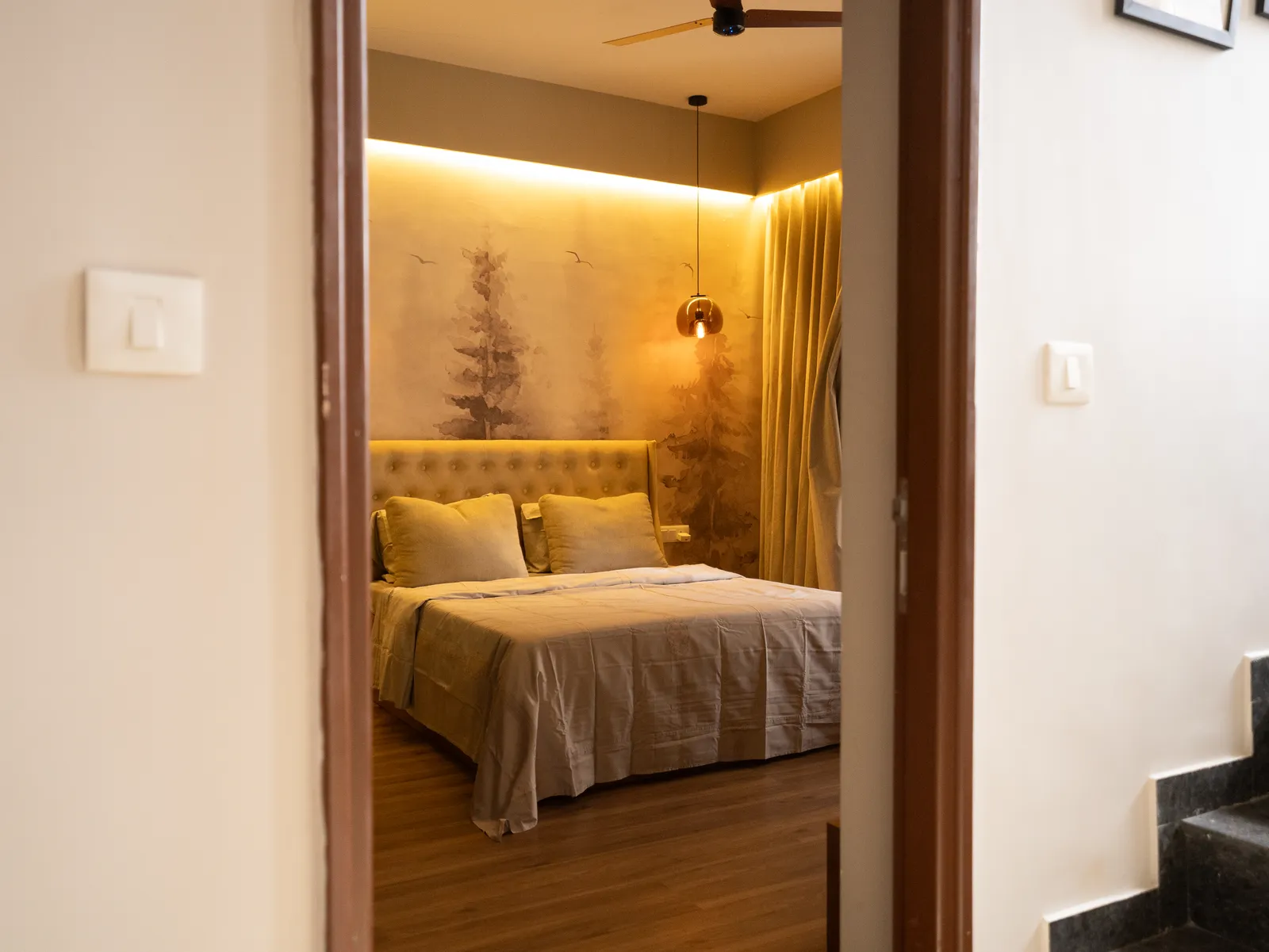 View into the bedroom with forest mural and tufted bed — Amlan's Residence